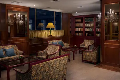a library with chairs and tables and bookshelves at Art Nouveau Palace Hotel in Prague