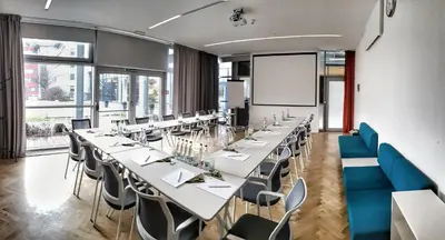 a conference room with long tables and blue chairs at Holiday Inn Prague Airport by IHG in Prague