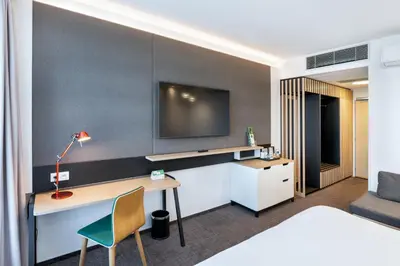 a hotel room with a desk and a tv on a wall at Holiday Inn Prague Airport by IHG in Prague