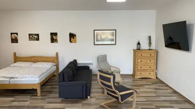 a bedroom with a bed and a couch and a chair at Apartmány Statek Bezdědice in Hostomice