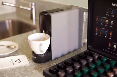 a coffee maker with a cup on a counter at Anděl Apartments Praha in Prague