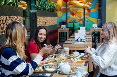 a group of women sitting at a table eating food at Anděl Apartments Praha in Prague