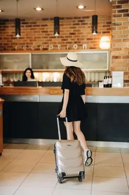 a woman in a hat is pulling a suitcase at Absolutum Wellness Hotel in Prague