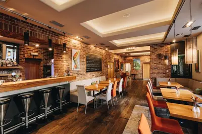 a restaurant with wooden tables and chairs and a brick wall at Absolutum Wellness Hotel in Prague