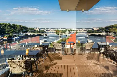 a balcony with tables and chairs and a view of a river at The President in Prague