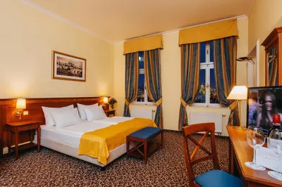a hotel room with a bed and two windows at Louis Leger - Czech Leading Hotels in Prague