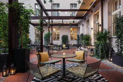 an outdoor patio with tables and chairs and plants at Falkensteiner Boutique Hotel Prague in Prague