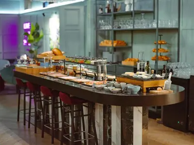 a buffet line with food on a table with stools at Falkensteiner Boutique Hotel Prague in Prague