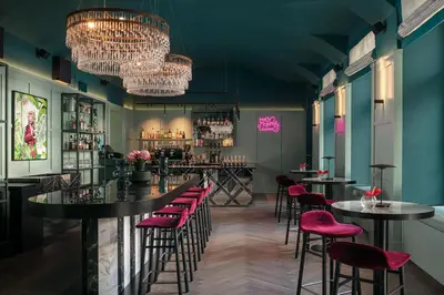 a bar with tables and chairs in a room with green walls at Falkensteiner Boutique Hotel Prague in Prague
