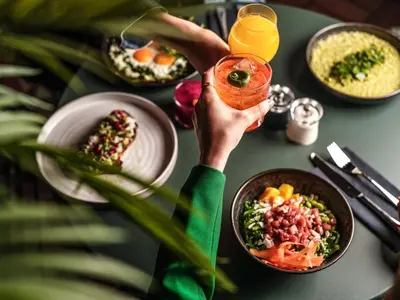 a person holding a drink over a table with food at Falkensteiner Boutique Hotel Prague in Prague