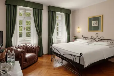 a bedroom with a large bed and a chair at Hotel Roma Prague in Prague