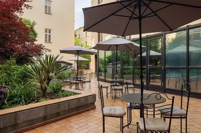 a patio with tables and chairs with umbrellas at Hotel Roma Prague in Prague