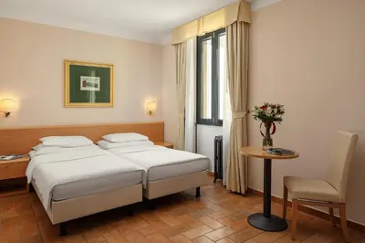 a bedroom with a bed and a table and a chair at Hotel Roma Prague in Prague