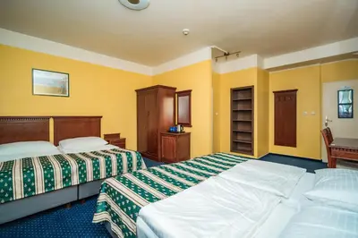 two beds in a room with yellow walls at Hotel Otakar in Prague