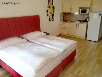 a bedroom with a red and white bed and a kitchen at Hotel Otakar in Prague