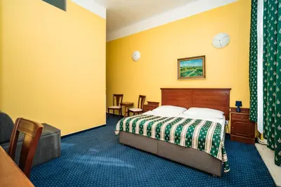 a hotel room with a bed and yellow walls at Hotel Otakar in Prague