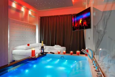 a bathroom with a large tub with a tv above it at Hotel Aura Design & Garden Pool in Prague