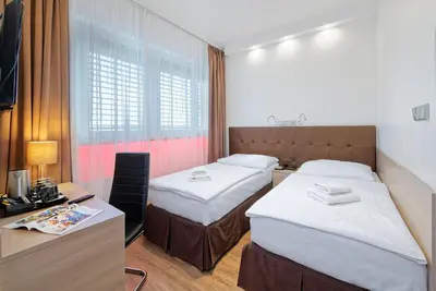 a hotel room with two beds and a desk at Hotel Aura Design & Garden Pool in Prague