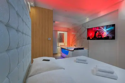 a bedroom with a bed and a tv on the wall at Hotel Aura Design & Garden Pool in Prague