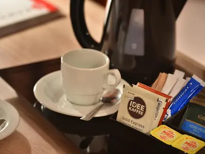 a coffee cup on a plate next to a coffee maker at Ramada Airport Hotel Prague in Prague