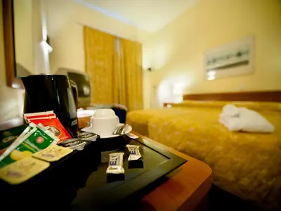 a hotel room with a bed and a table with a tray of food at Ramada Airport Hotel Prague in Prague
