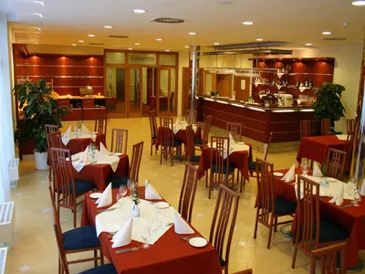a restaurant with red tables and chairs and a bar at Ramada Airport Hotel Prague in Prague
