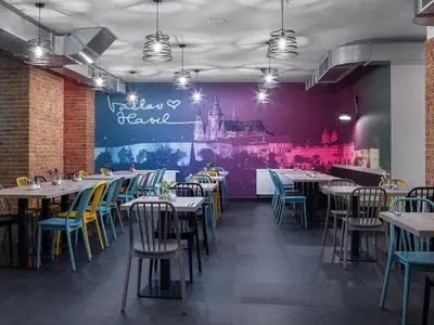 a dining room with tables and chairs and a wall with a castle at EA Hotel Rokoko in Prague