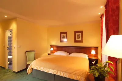 a bedroom with a bed and a green chair at EA Hotel Jeleni Dvur Prague Castle in Prague