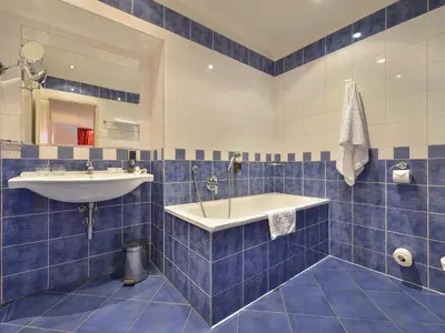 a blue tiled bathroom with a sink and a tub at EA Hotel Jeleni Dvur Prague Castle in Prague