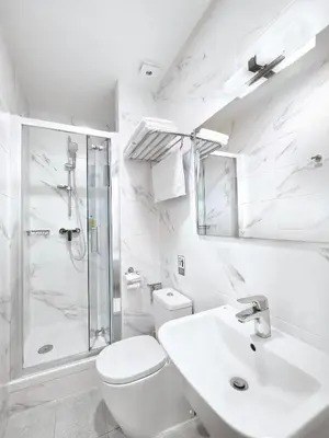 a white bathroom with a sink and a shower at Hotel Melantrich Old Town in Prague