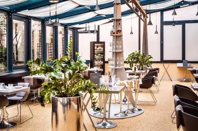 a restaurant with tables and chairs and plants at Grandium Hotel Prague in Prague