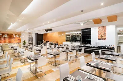 a restaurant with white chairs and tables and a bar at Grandium Hotel Prague in Prague