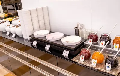 a counter with white plates and jars of food at Grandium Hotel Prague in Prague