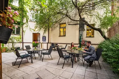 a man and a woman sitting at tables in a courtyard at Hotel U Divadla - Czech Leading Hotels in Prague
