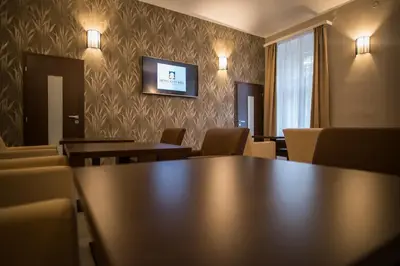 a conference room with tables and chairs and a tv on the wall at Hotel City Bell in Prague