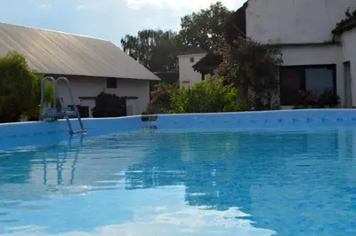 a blue swimming pool with a chair in front of a house at Bohemica Apartman 3 in Kouřim