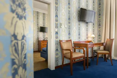 a room with a table and chairs and a television at Hotel Rott in Prague