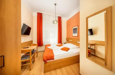 a bedroom with a bed and a desk and a mirror at Hotel Golden City Garni in Prague
