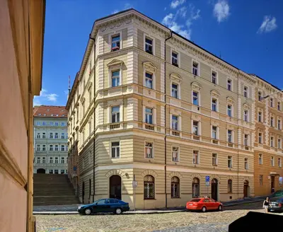 a large building with two cars parked in front of it at Hotel Golden City Garni in Prague