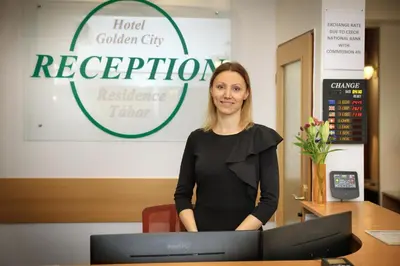 a woman standing in front of a reception desk at Hotel Golden City Garni in Prague