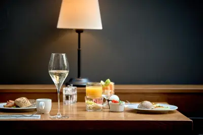 a table with a glass of wine and plates of food at Hotel Schwaiger in Prague
