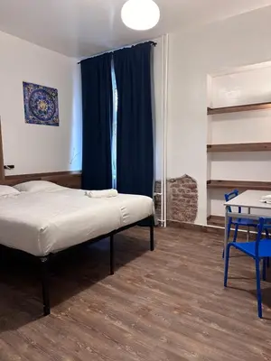 a bedroom with a bed and a table and blue curtains at Gallery Hotel SIS in Prague