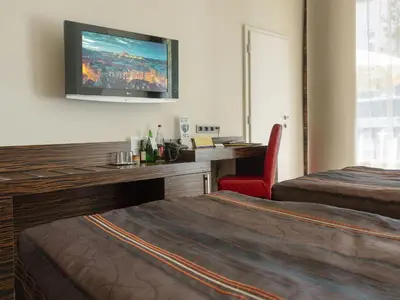 a hotel room with two beds and a desk with a television at EA Hotel Crystal Palace in Prague