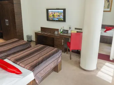 a room with two beds and a desk with a television at EA Hotel Crystal Palace in Prague