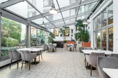 a restaurant with tables and chairs and windows at Hotel Troja in Prague