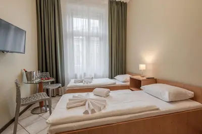 a hotel room with two beds and a window at Hotel Brixen in Prague