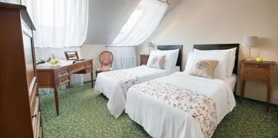 a hotel room with two beds and a desk at Hotel Angelis in Prague