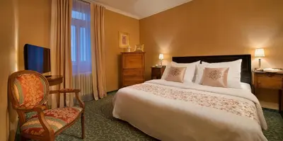 a bedroom with a bed and a chair and a television at Hotel Angelis in Prague