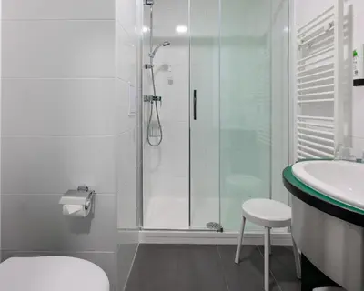 a bathroom with a shower and a toilet and a sink at Hotel Malá Strana in Prague