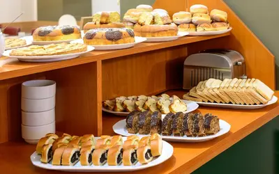 a shelf with different types of pastries on plates at Hotel Malá Strana in Prague